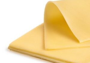 Folded thin slice of yellow cheese on top of a stack of yellow cheese slices.